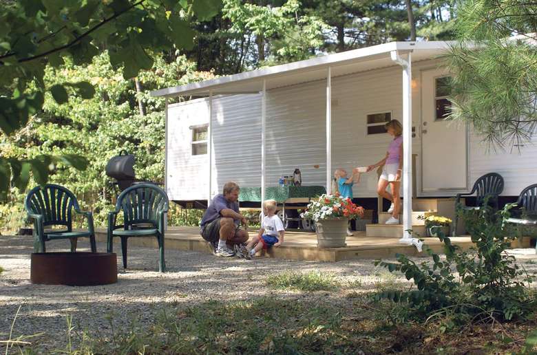a family hanging out on a porch in front of a trailer