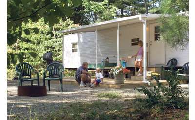 a family hanging out on a porch in front of a trailer