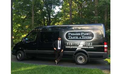driver in a suit standing in front of a premier plus travel and tours van
