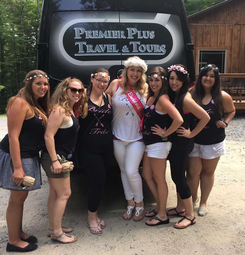 seven members of a bachelorette party standing in front of a premier plus travel and tours van