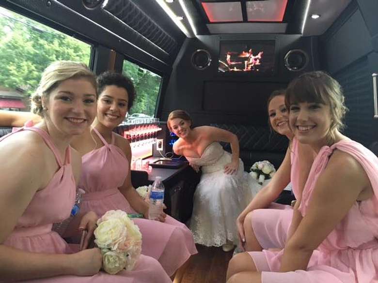 bride and bridesmaids in a limo-style van