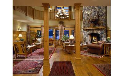 great room at fern lodge with wooden columns and a stone fireplace