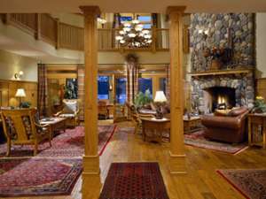 great room at fern lodge with wooden columns and a stone fireplace