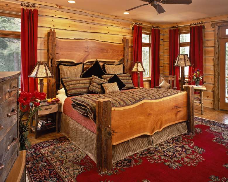 a bedroom decorated in wood panels with a wooden bed and dresser, red curtains