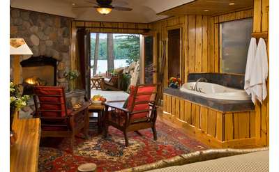 a hot tub in a living room with as tone fire place, view of a patio outside