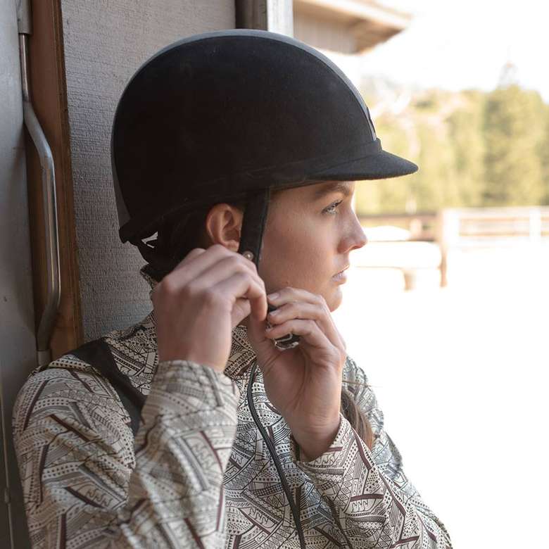woman buckling an equestrian helmet