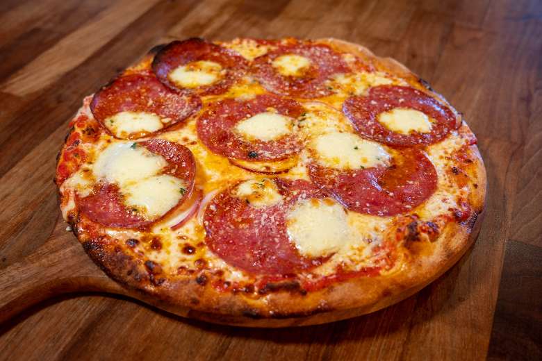 Pizza with salami and cheese on a wooden pizza pattle