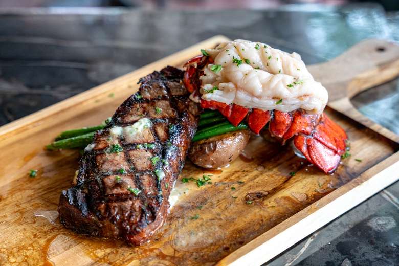 steak and lobster tail on a wooden platter