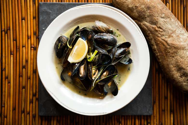 mussels and a lemon wedge in a bowl of butter sauce