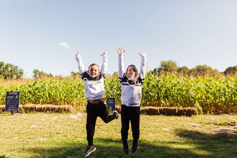 Children jumping in front of corn maze