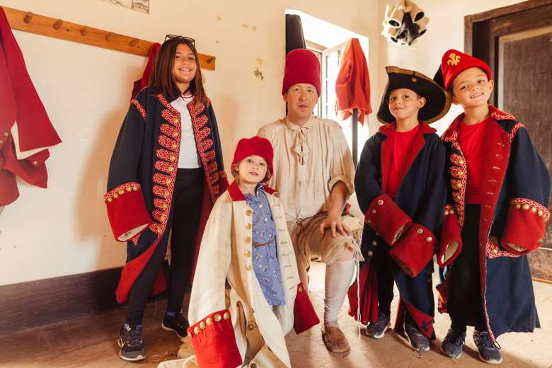 Children with interpreter trying on historic coats