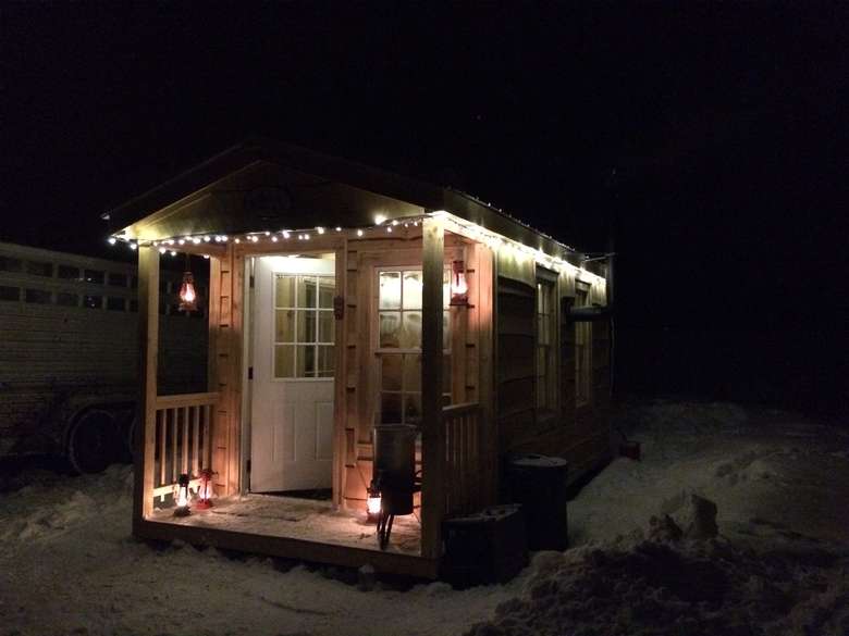 a wooden cabin with lights on it during the evening