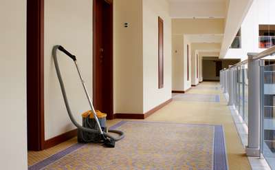 a long carpeted hallway with carpet cleaning equipment against the wall