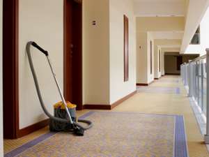 a long carpeted hallway with carpet cleaning equipment against the wall