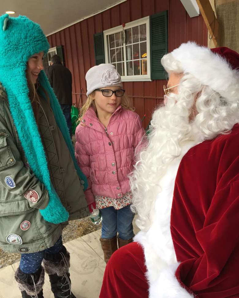 santa meeting with two girls at a farm