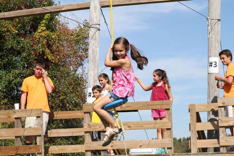 girl swinging on a zipline while other kids look on