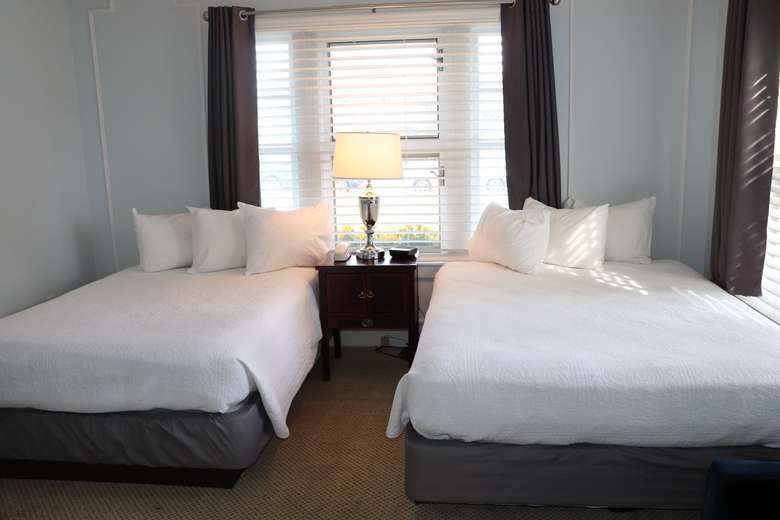 view of both beds in first bedroom, there's a nightstand, lamp and large window in between the beds