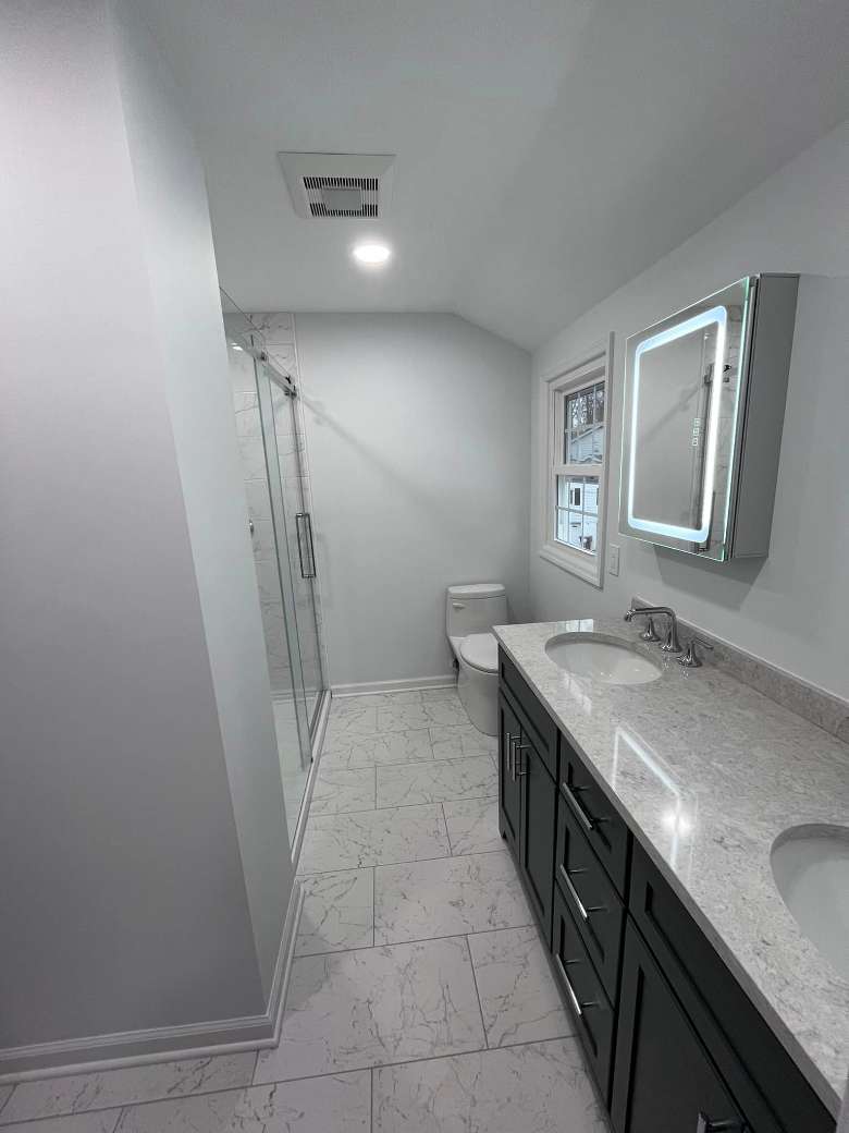 a bathroom with a long sink area and a toilet and shower in the back