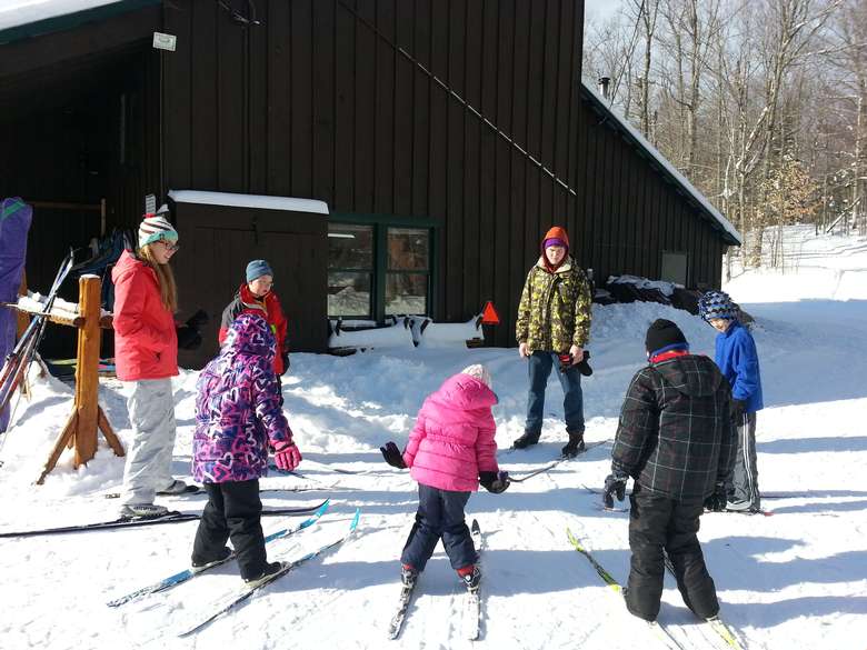 kids with an adult and instructor with skis on prepared for their lesson