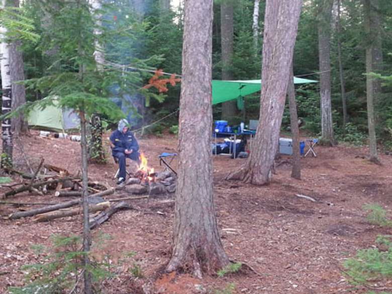boy sitting by a campfire at a campsite