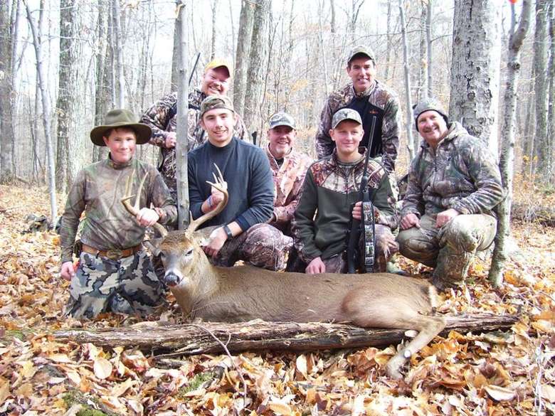 group of hunters posing around a deer