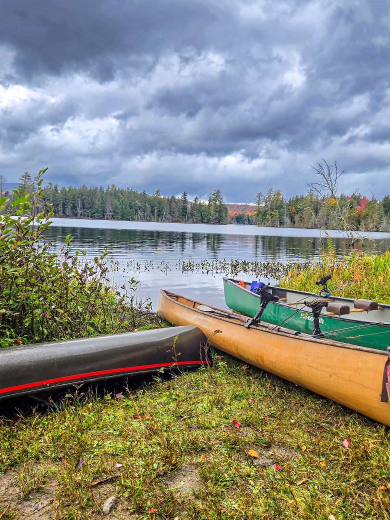 three canoes on the shoreline of a pond