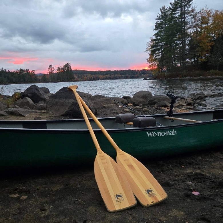 a green canoe with two wooden paddles