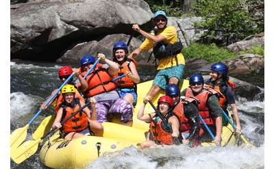 large group of whitewater rafters on a yellow raft