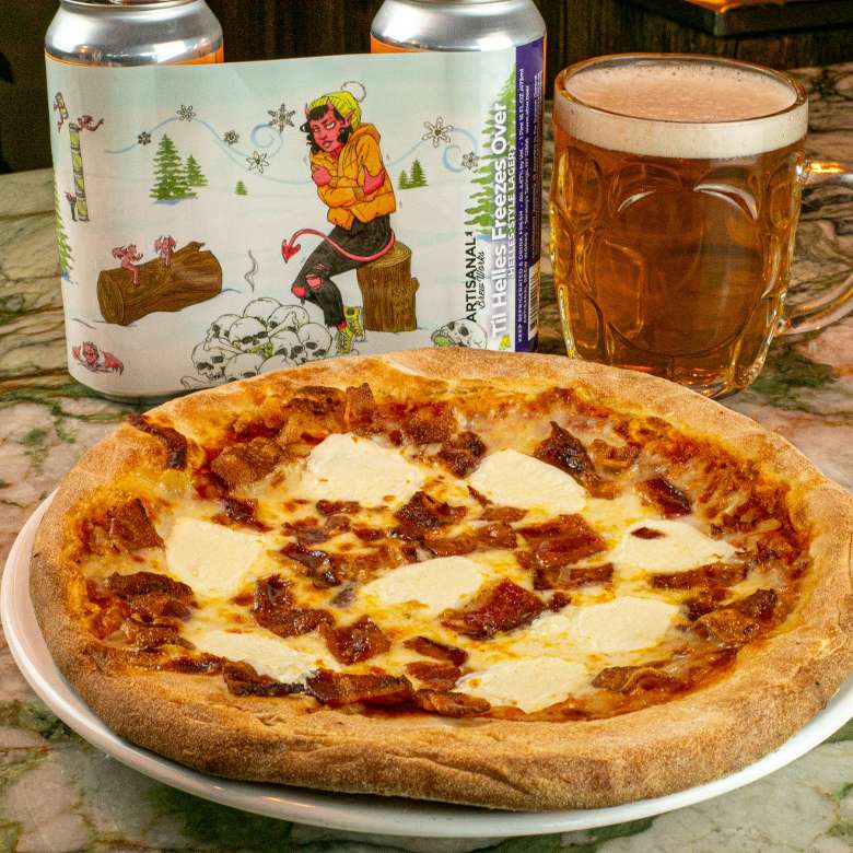 pizza next to a glass of beer and two beer cans.