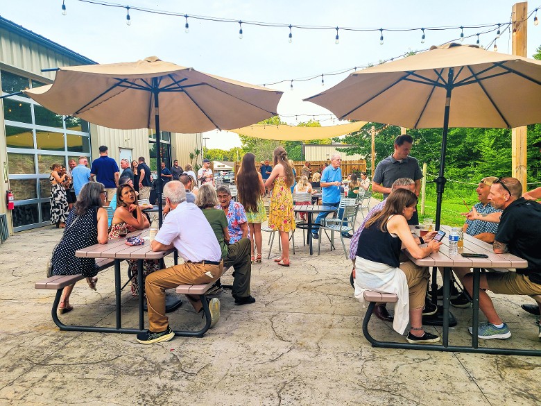 Outdoor dining patio with guests at Artisanal Brew Works restaurant in Saratoga Springs NY