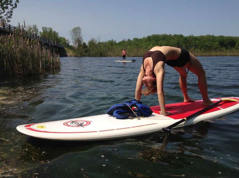 woman doing a back bend on a stand-up paddle board
