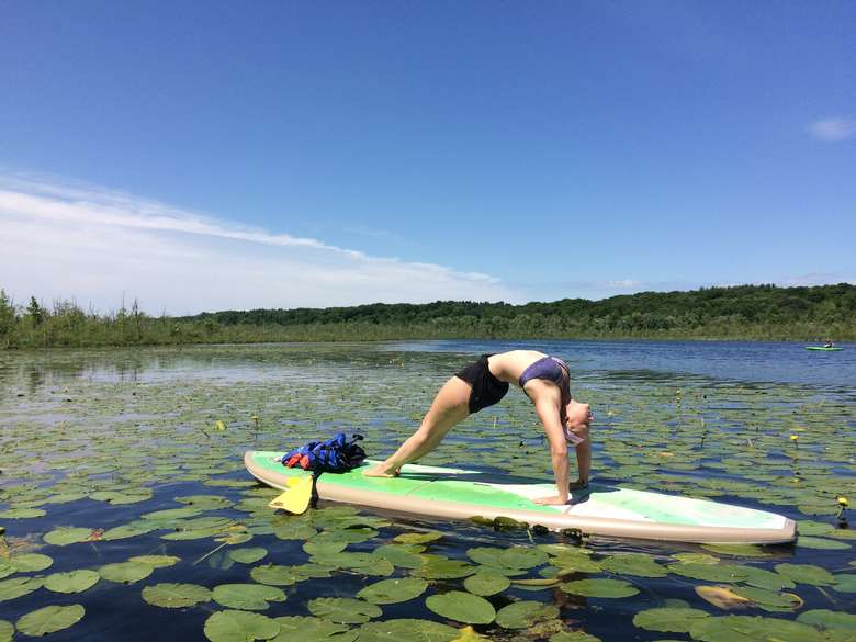 woman doing sup yoga in a patch of lily pads
