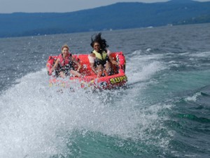 two people in a tube pulled behind a boat