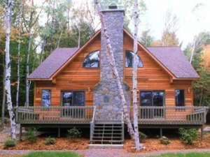 a brown wooden home with a stone chimney and front porch