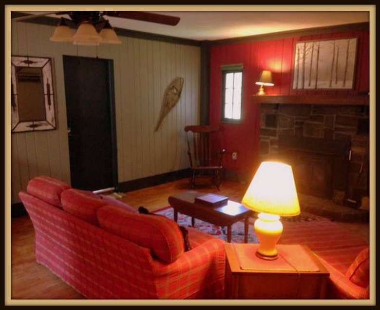 red couch in a sitting room with a fireplace, a red wall, and a light green wall