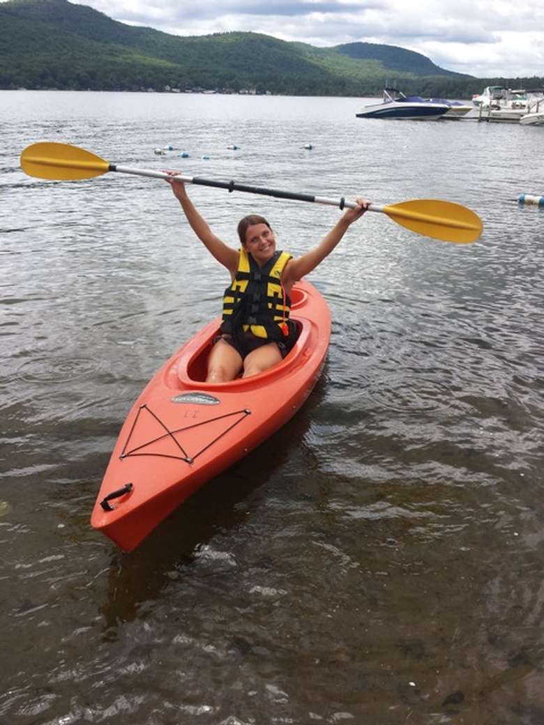 girl in a kayak holding a paddle over her head
