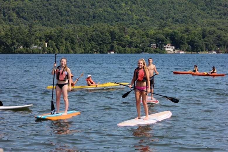 group of people stand-up paddleboarding on lake george