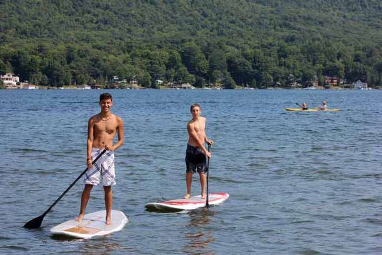 two men stand-up paddleboarding on lake george