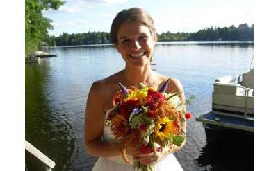 bride smiling and holding a colorful bouquet with a lake in the background 