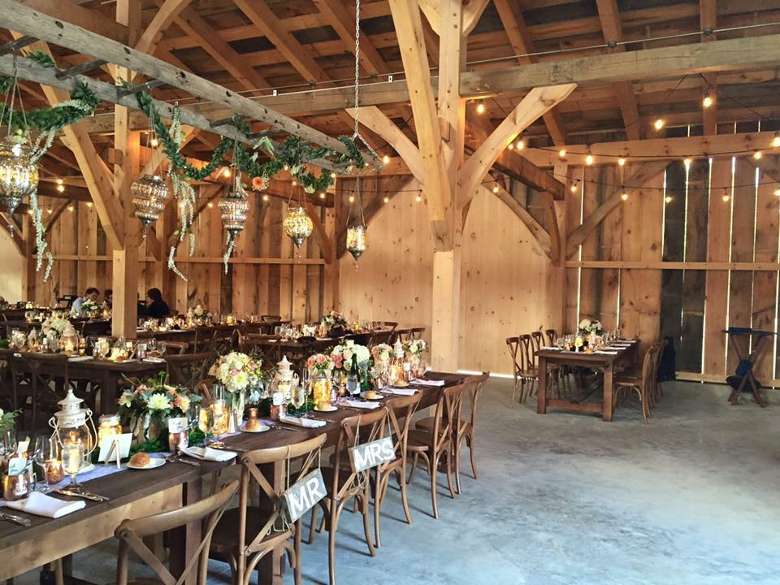 tables in a rustic barn set up for a wedding reception