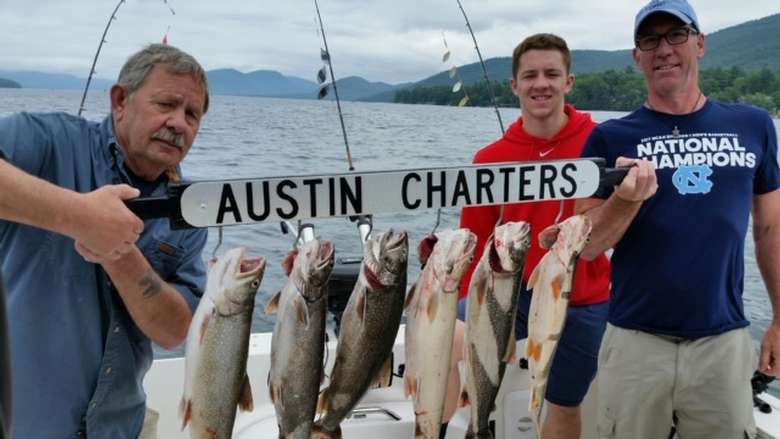 three people holding an austin charters catch board with hanging fish