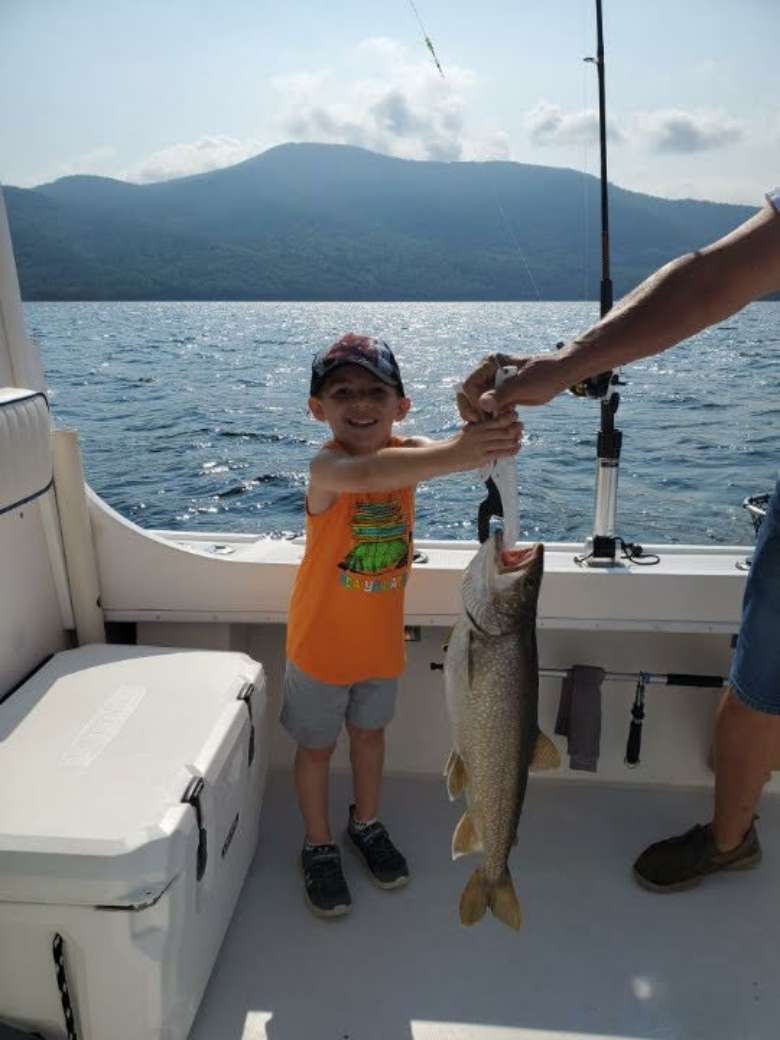 kid with fish on boat