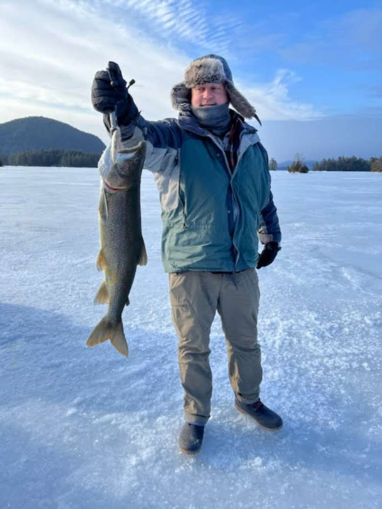 man holds up fish in winter