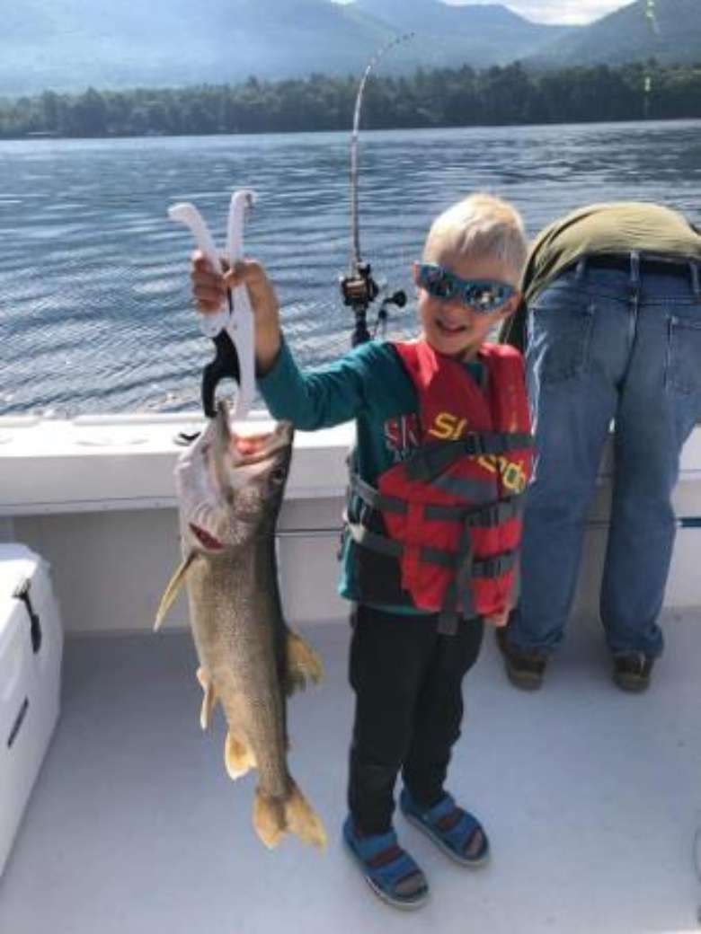 kid holds up fish on boat