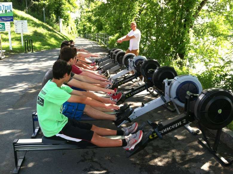 Man training kids while they row on machines