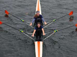 Two girls looking up at the camera smiling while rowing