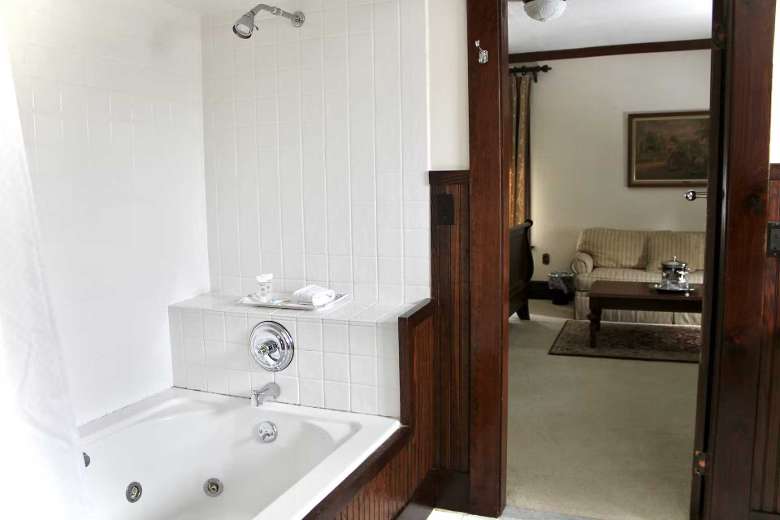 view of living room area from a bathroom with a tub