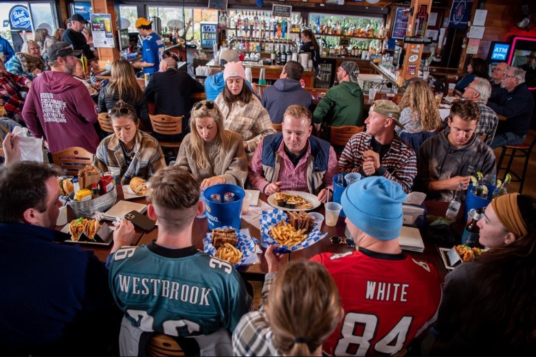 people eating food, wearing football jerseys