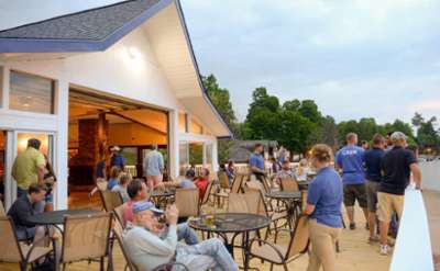 People at tables outdoors with waitstaff