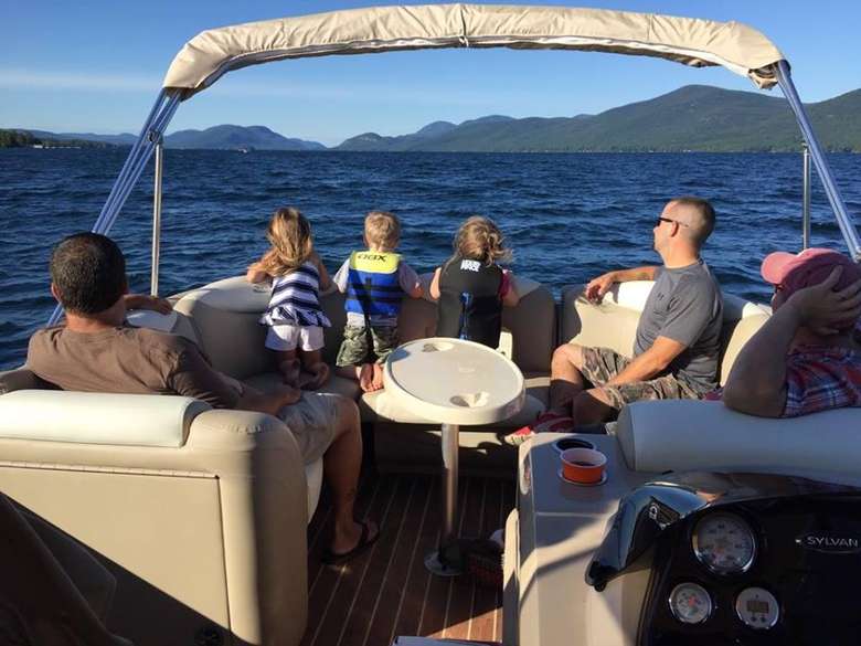 Family on a boat tour of Lake George with mountains in the background